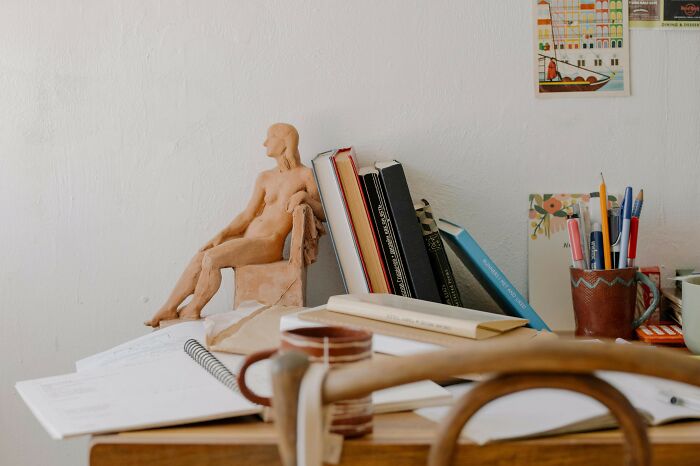 Desk with books, notebooks, pens, and a sculpture, illustrating everyday words for language translation practice. Desk with books, notebooks, pens, and a sculpture, illustrating everyday words for language translation practice.