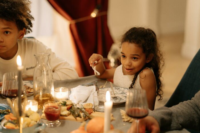 Children enjoying Thanksgiving dinner amid mashed potatoes and holiday conversation at a festive family table setting.