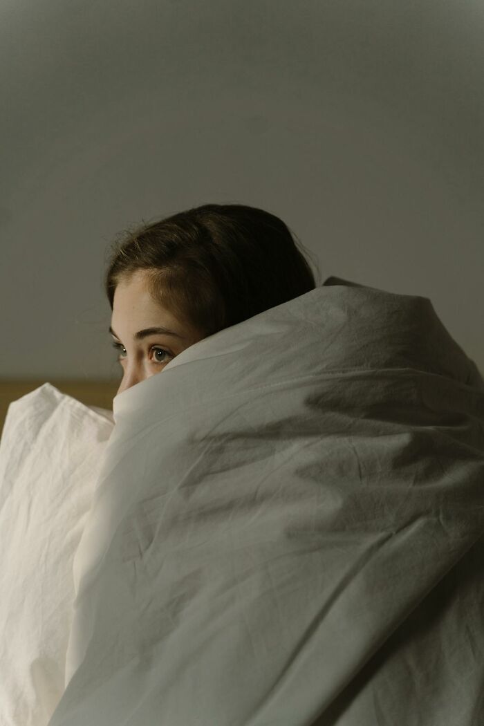 Young woman wrapped in a white blanket, reflecting on the experience of dying as shared by people who came back to life.