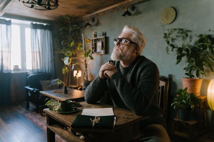 Elderly man with glasses sitting thoughtfully at a wooden table reflecting on harsh truths about marriage reality.
