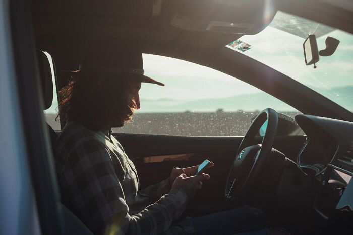 Man in a truck at sunset using phone, illustrating haunting things truckers have seen on the road at night.