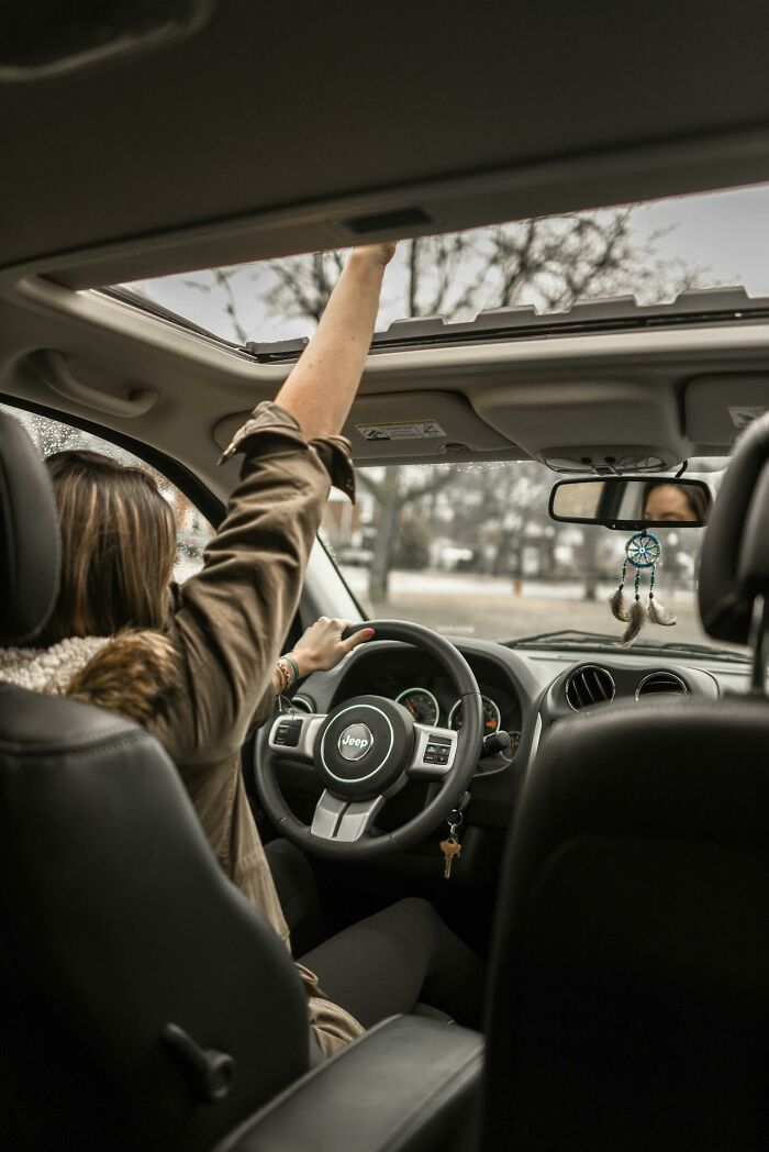 Woman driving a Jeep with her arm raised through the sunroof, illustrating childhood habits that were anything but normal.