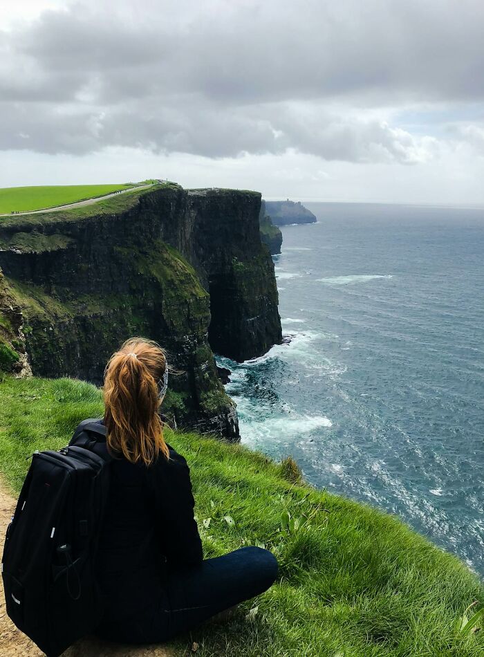 Person sitting on cliff edge overlooking ocean, capturing bizarre moments that made people wonder about sanity.