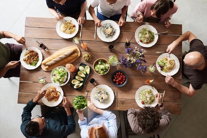 Group of people sitting around a table sharing a meal, showcasing childhood habits realized as unusual or unique.