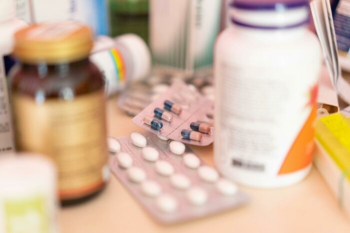 Various medicine bottles and blister packs of pills scattered on a table, illustrating relatable everyday health habits.