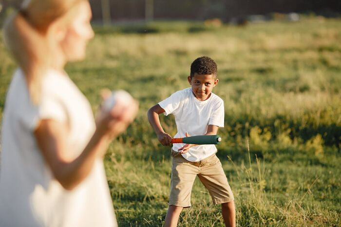 Young boy playing baseball with a parent outdoors, capturing funny and serious moments parents realize they are raising monsters.