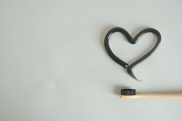 Heart shape created with black toothpaste next to bamboo toothbrush symbolizing petty and brutal revenge on an ex.