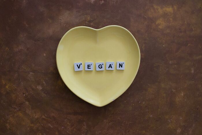 Heart-shaped plate with letter tiles spelling vegan, symbolizing petty revenge on an ex with zero regrets.