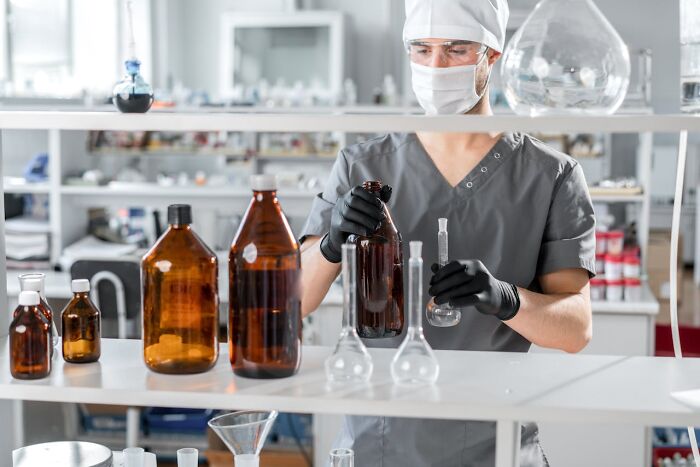 Laboratory technician handling large bottles of chemicals in a lab environment related to garbage men finding horrifying items on the job