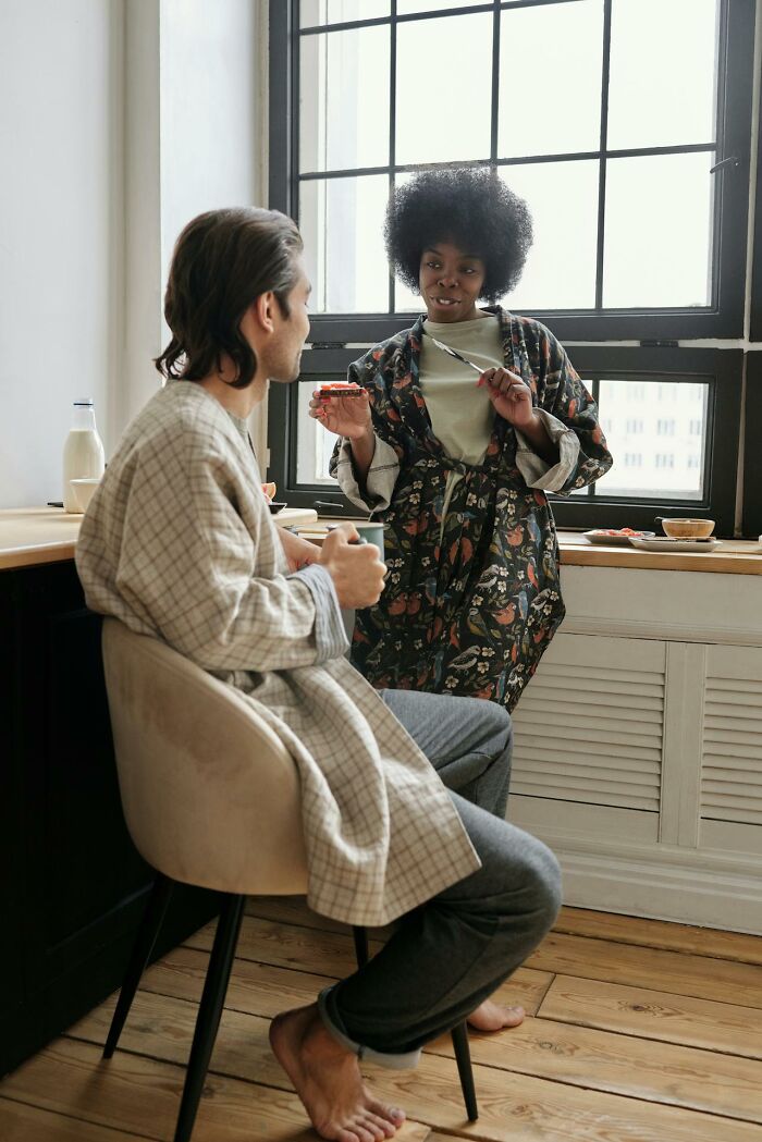 Couple in cozy robes having a morning conversation in bright kitchen, reflecting on harsh truths about marriage reality.