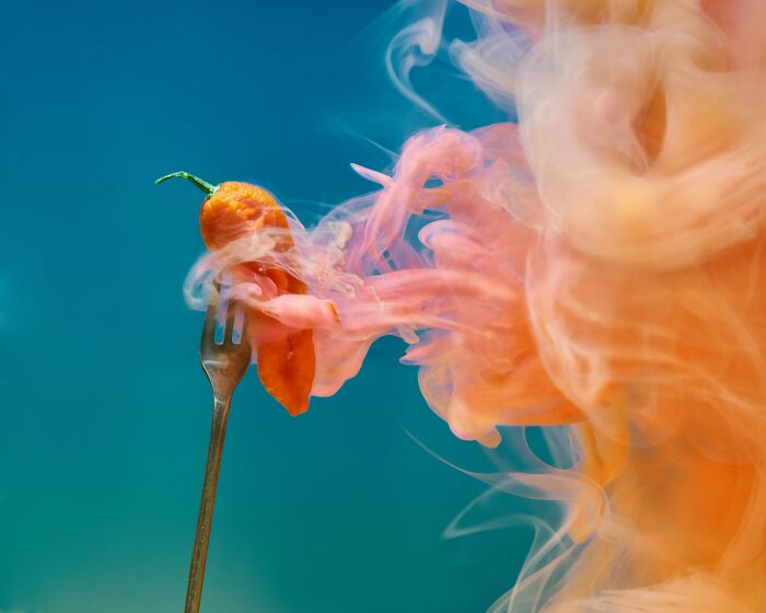 Orange hot chili pepper on a fork emitting swirling smoke, representing visual thinkers in odd-one-out questions.