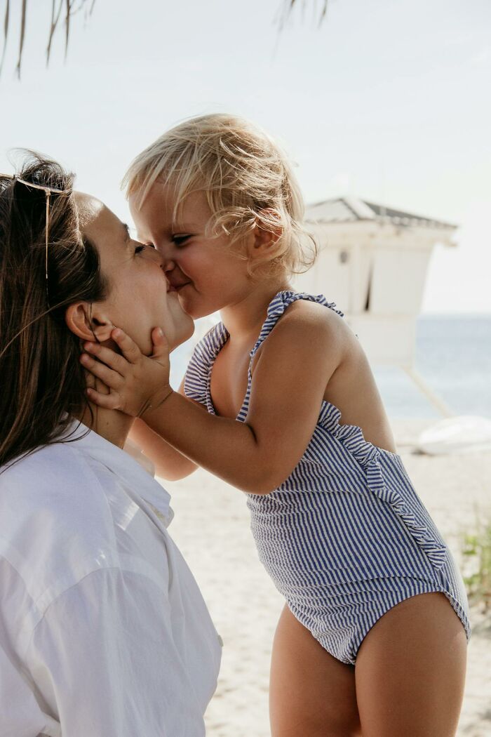 Mother and child sharing a close moment at the beach, highlighting childhood habits that seem unusual or not normal.