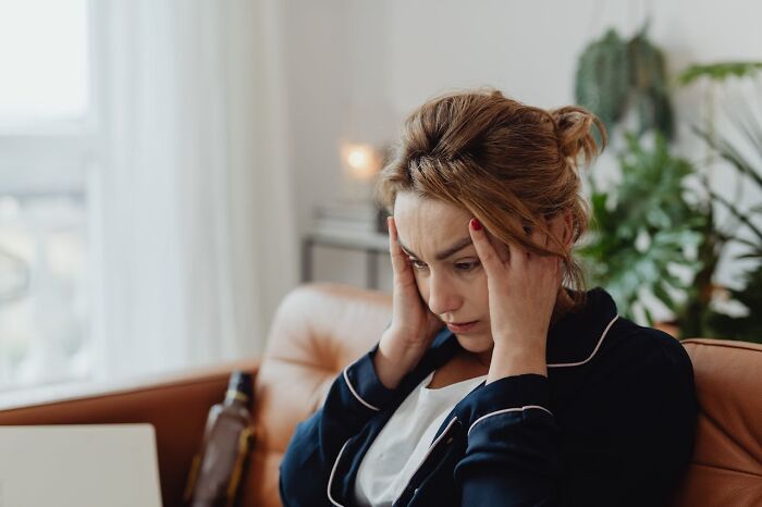Woman sitting on a couch looking stressed and overwhelmed during bizarre moments that made people question their sanity.