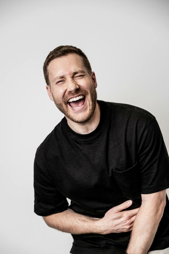 Man in black shirt laughing heartily, capturing a bizarre moment that makes people wonder about sanity.