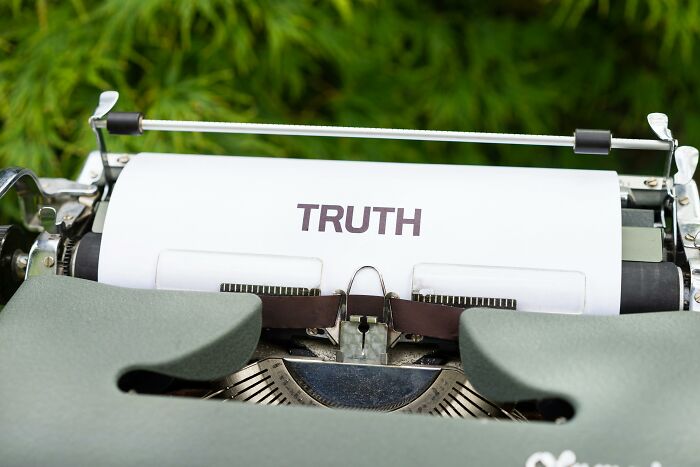 Typewriter with a sheet of paper displaying the word truth, symbolizing a truth or lie quiz concept outdoors.