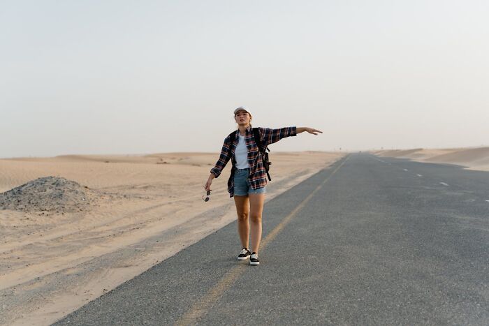 A woman walking alone on a deserted road in the desert, representing nurses of psych wards sharing intense stories.