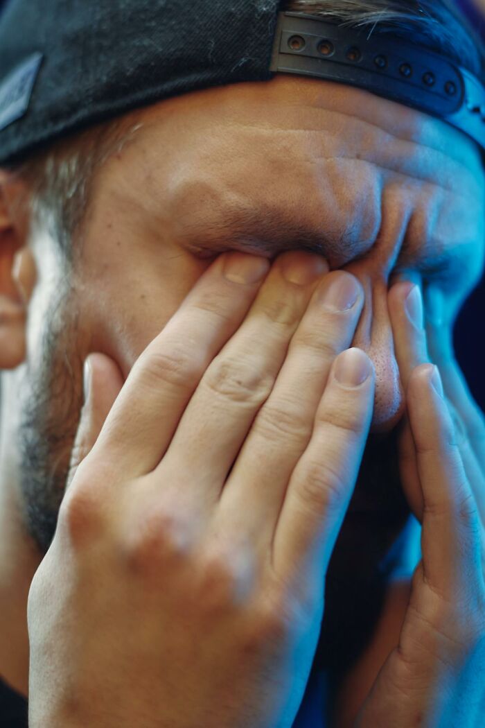 Stressed trucker covering face, feeling overwhelmed by haunting things seen on the road at night.