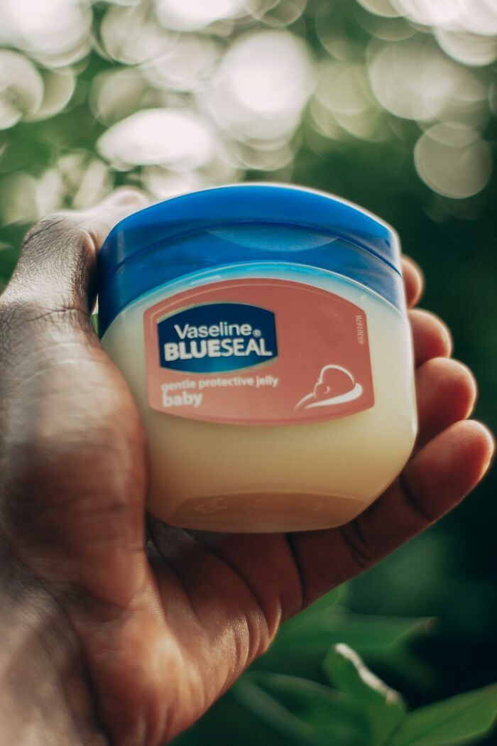 Hand holding a jar of Vaseline BlueSeal with blurred natural background, reflecting care in psych wards nurses stories.