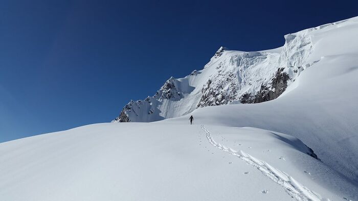 A lone hiker traversing a vast snowy mountain landscape, evoking bizarre and creepy park ranger experiences.