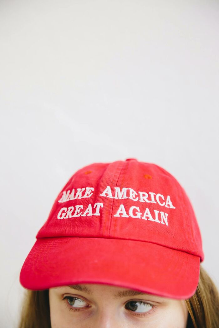 Person wearing a red cap with a bold slogan, highlighting bizarre moments that made people question their sanity.