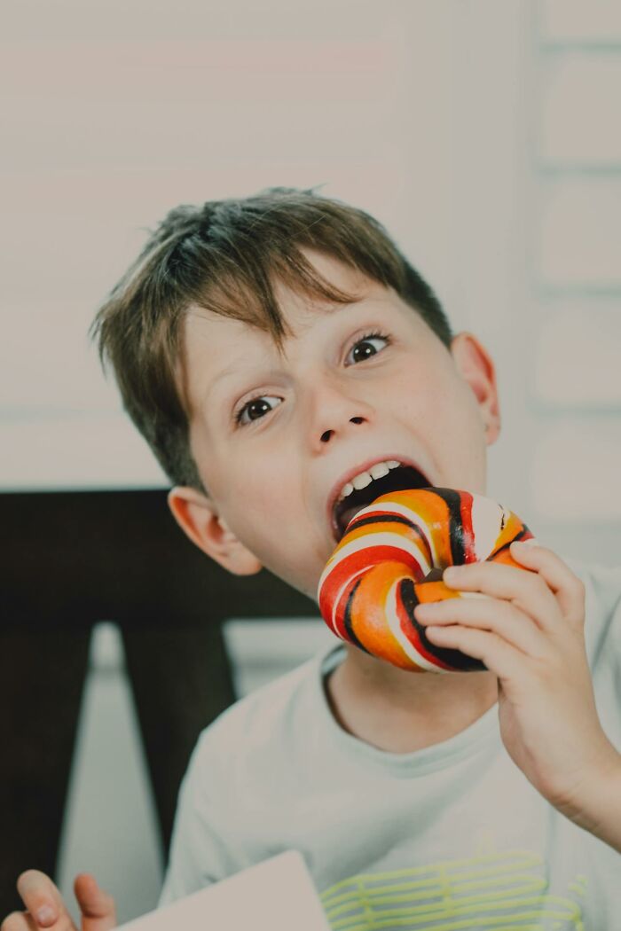 Young boy eating a colorful striped donut showcasing funny and serious moments parents realized they were raising monsters.