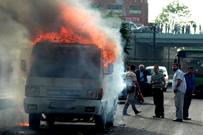 Garbage men witnessing a van engulfed in flames on a busy street, highlighting horrifying finds on the job.