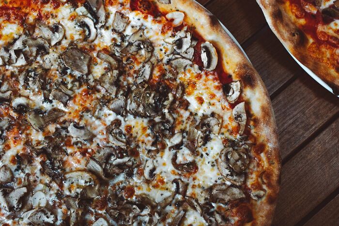 Close-up of a mushroom pizza on a wooden table, highlighting texture and crispy crust for park rangers and hikers.