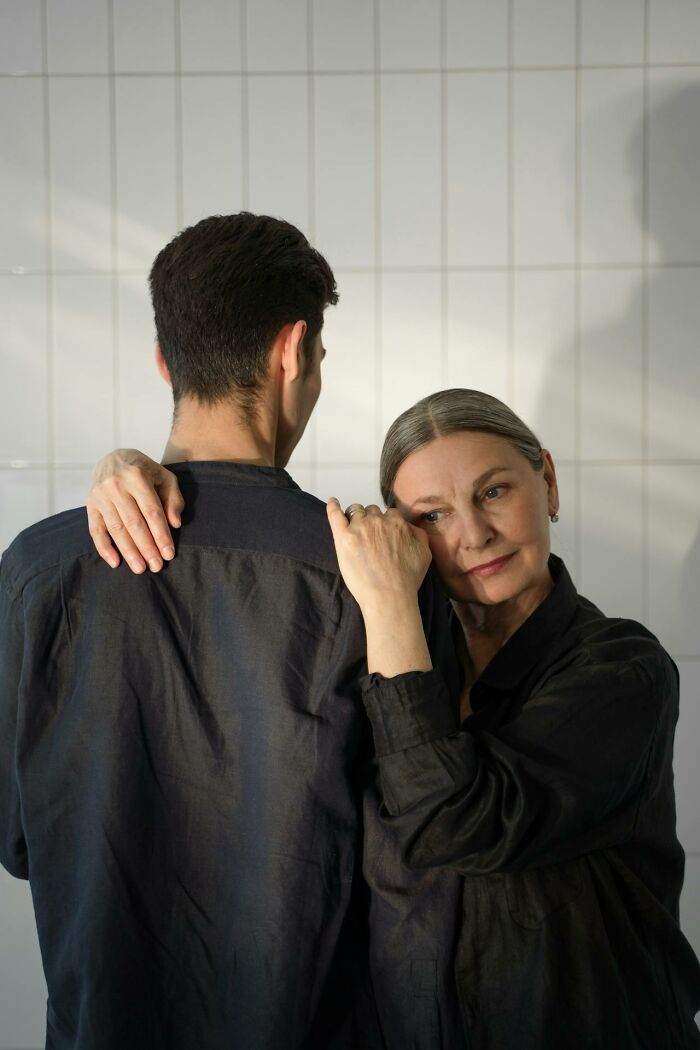 Older woman embracing younger man, sharing a heavy confession moment in an intimate and emotional setting.