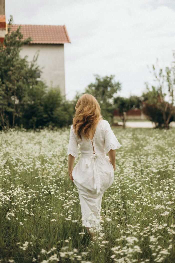 Woman in white dress walking through a field of flowers, reflecting on experiences of people who came back to life.