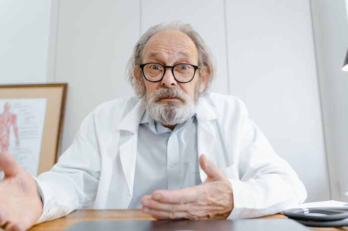 Older male doctor with glasses explaining mysterious medical issues and clear diagnoses in a clinical setting.