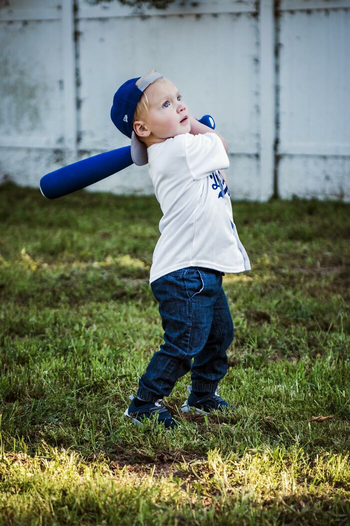 Young child swinging a blue baseball bat outdoors, capturing funny and serious moments parents realize they are raising monsters.