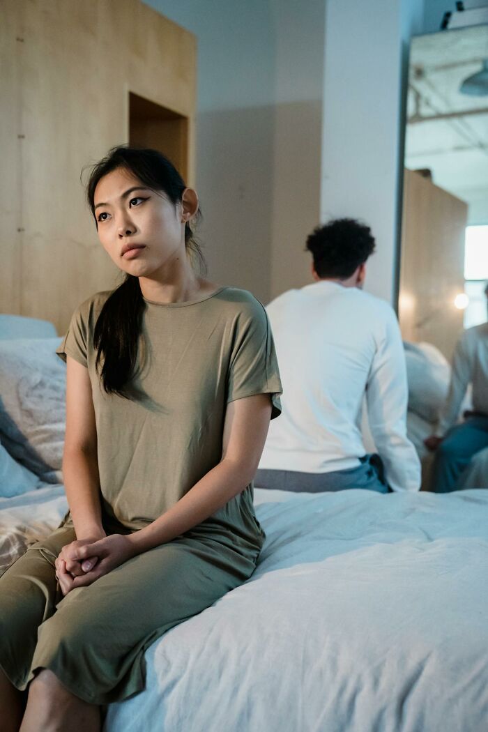 Woman sitting on bed looking away with upset expression while man faces away, showing harsh truths about marriage struggles.