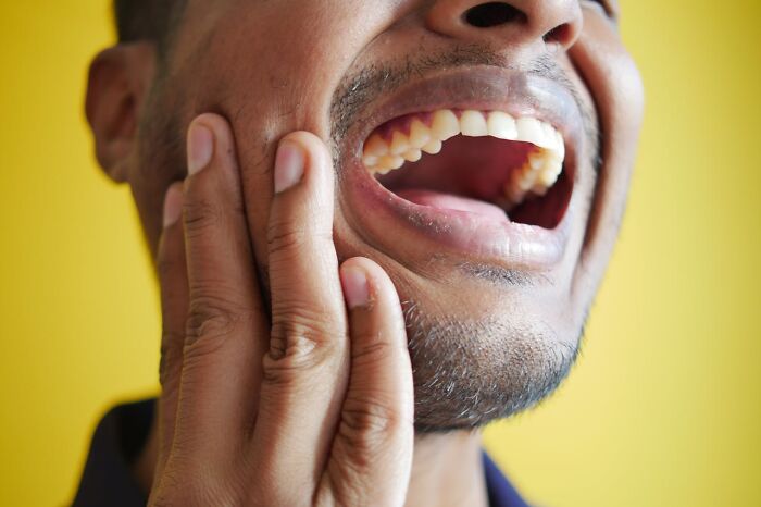 Close-up of man holding jaw in pain, illustrating intense experiences shared by nurses of psych wards.