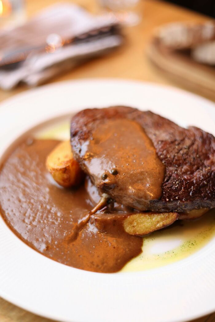 Close-up of steak with sauce and roasted potatoes on a white plate, illustrating unusual childhood habits and food preferences.