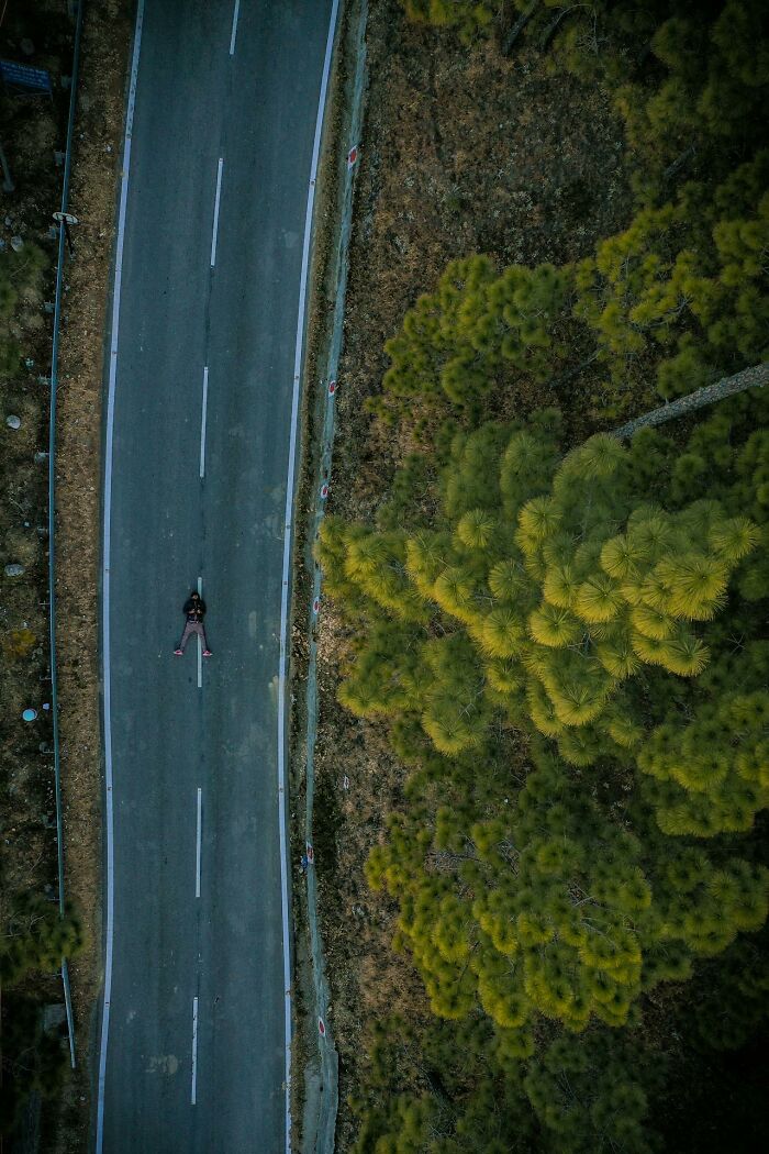 Person lying in the middle of an empty road at night surrounded by trees, evoking haunting things truckers have seen on the road.