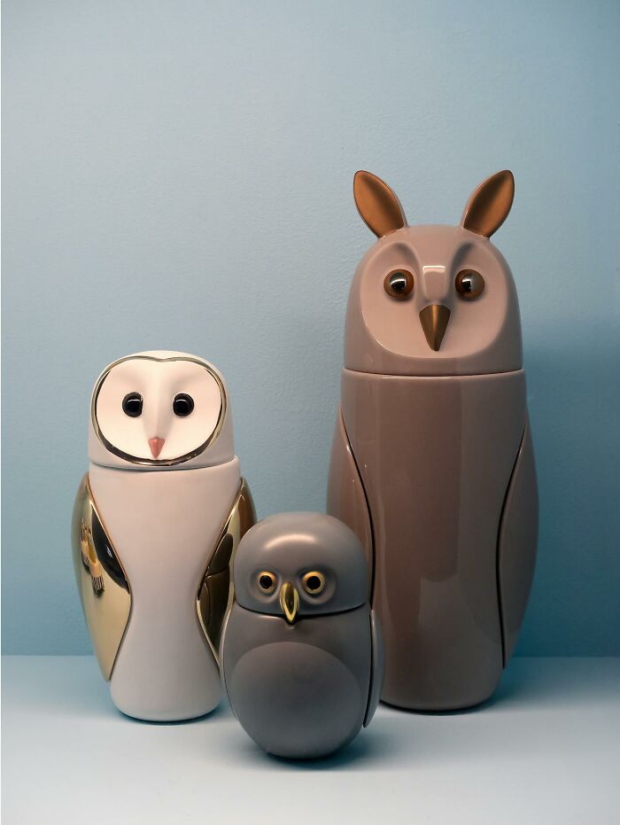 Three owl-shaped containers in white, gray, and brown colors arranged against a plain blue background.