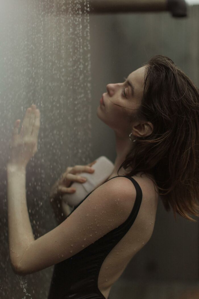 Young woman in the shower reflecting, highlighting childhood habits that were anything but normal from early experiences.