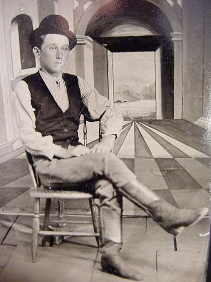 Young man from the past sitting in a wooden chair, showcasing very old objects that reveal stories about ancestors.