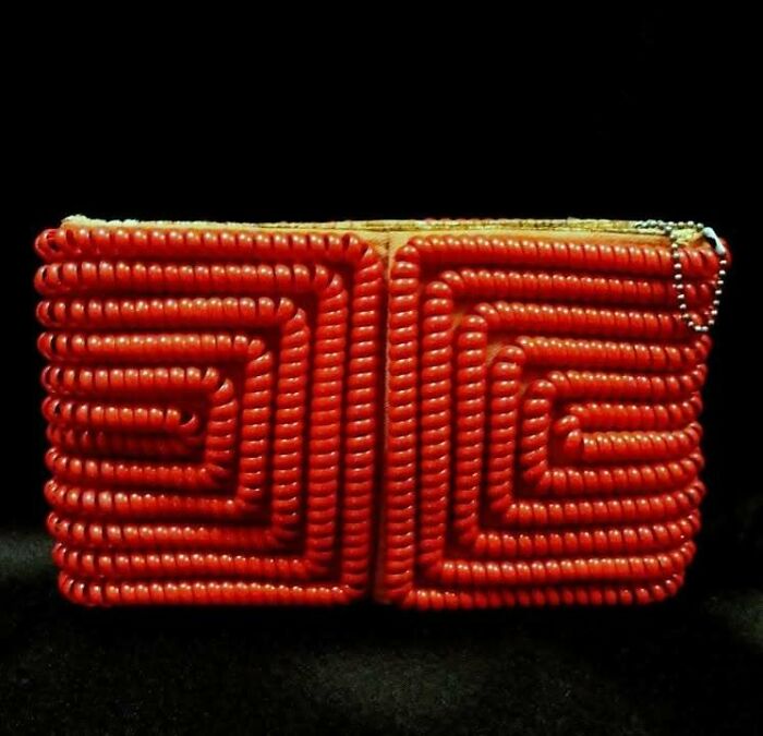 Ancient red beaded artifact with intricate spiral patterns, a very old object surviving from our ancestors' time.