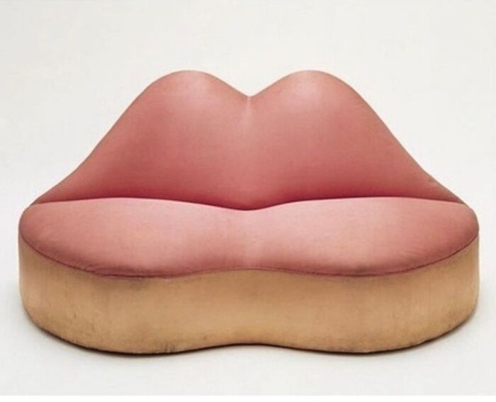 Vintage lips-shaped sofa in pink and beige colors, a very old object showcasing unique design from our ancestors.
