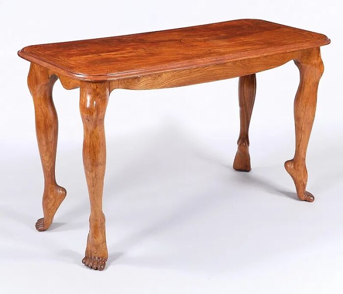 Wooden table with uniquely carved legs resembling human feet, an old object showcasing craftsmanship from our ancestors.