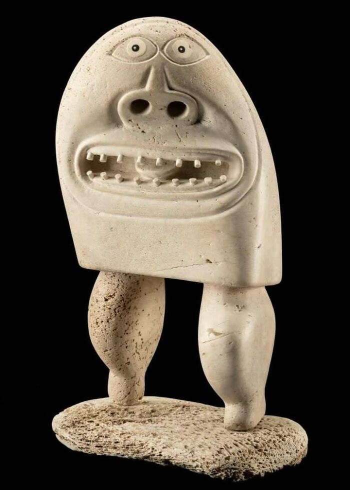 Ancient carved stone sculpture with face and legs, a very old object showing ancestral artistry and storytelling.