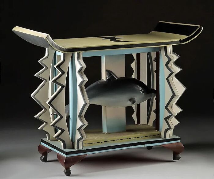 Antique wooden stool with carved zigzag patterns and a fish sculpture, a very old object showing stories about ancestors.