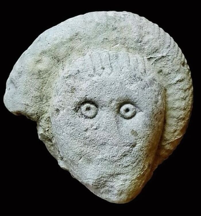 Ancient carved stone face with distinct eyes and hair, one of the very old objects surviving from our ancestors' era.