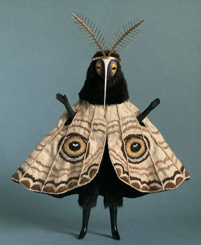 Antique handcrafted figure resembling an insect with detailed wings and intricate headpiece, showcasing old objects from ancestors.