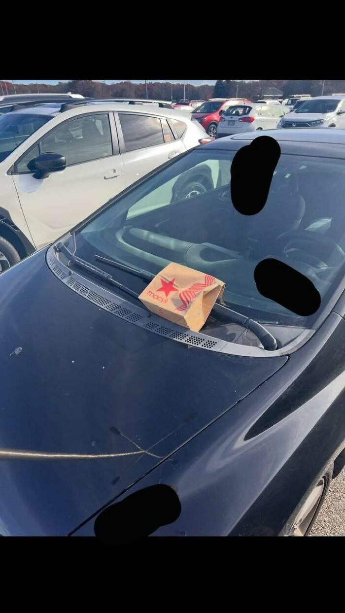 Paper bag placed on a car windshield wiper in a crowded parking lot, illustrating messy times people turn to the internet.