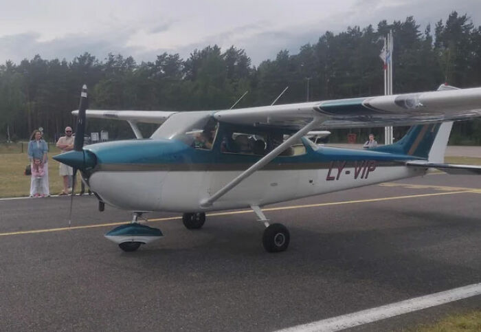 Small blue and white airplane on runway with passengers and spectators nearby, illustrating pilots handling terrifying situations calmly.
