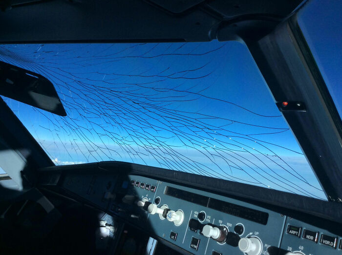 Cockpit view showing cracked windshield during flight, illustrating terrifying situations pilots handled with calmness inside.