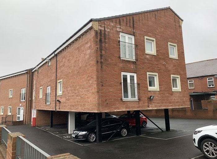Unusual building design with a house elevated on stilts above parking, showcasing design and architecture nightmares.