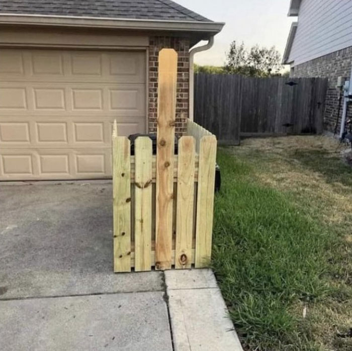 Wooden fence blocking driveway entrance showing design and architecture nightmares with poor common sense in residential area.
